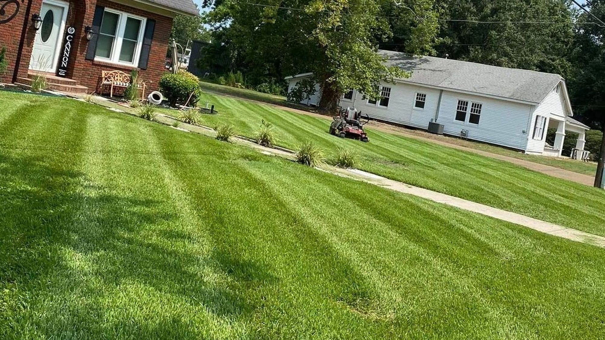 A Mississippi Delta home with its lawn freshly cut and striped by Clark Bros, beds edged along the front walk